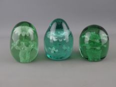 THREE VICTORIAN GREEN GLASS DUMP PAPERWEIGHTS, all having floral inclusions, 11 cms high the