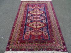 A PERSIAN STYLE MULTI-COLOUR TASSEL ENDED CARPET, multiple bordered edging with central repeating