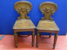 A PAIR OF VICTORIAN MAHOGANY SHIELDBACK HALL CHAIRS having scrolled decoration and tapering