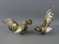 A PAIR OF STERLING SILVER & GILT DECORATED TABLE COCKERELS, 16 cms long approximately, marked '