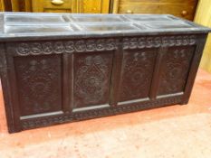 AN ANTIQUE BLACKENED OAK LIDDED PANELLED COFFER, having carved front detail, 68 cms high, 152 cms