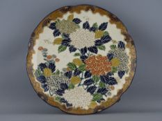 AN EARLY 20th CENTURY JAPANESE SATSUMA POTTERY WALL CHARGER having enamel decorated floral pattern