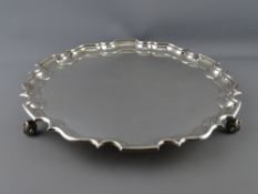 A FINE UNINSCRIBED CIRCULAR SILVER TRAY having a shaped and stepped border on three scrolled