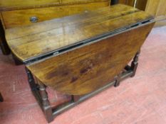 AN OAK TWIN FLAP GATE LEG DINING TABLE with single end drawer in the antique style on turned and