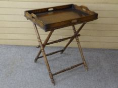 A VINTAGE OAK BUTLER'S TRAY ON FOLDING TURNED WOODEN STAND, 75 cms high, 68.5 x 47 cms the tray