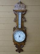 A VINTAGE ANEROID BAROMETER with ceramic dial and thermometer, set on a carved oak mount, 92 cms