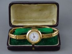 A NINE CARAT GOLD LADY'S VINTAGE WRISTWATCH on bracelet strap, the gilt decorated white dial set