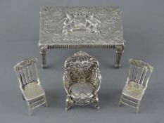FOUR ITEMS OF MINIATURE SILVER FURNITURE to include a rectangular table with coat of arms
