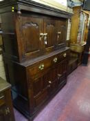 AN ANTIQUE OAK DEUDDARN having shaped and chamfered door panels with a central frieze of three