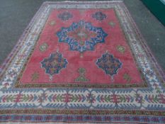 A PINK GROUND PERSIAN STYLE CARPET, classical style central pattern and multi-bordered edge with