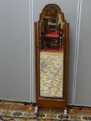 A CIRCA 1930 WALNUT FRAMED CHEVAL DRESSING MIRROR with shaped top bevelled edge glass, 146 cms high,