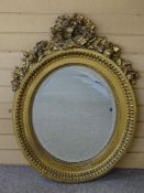 A GILT DECORATED OVAL WALL MIRROR, the bevelled edged plate surrounded by egg and dart moulding to