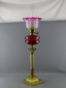 A VICTORIAN CORINTHIAN COLUMN BRASS OIL LAMP with cranberry font and tinted shade, 82 cms high