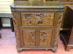 A CARVED ORIENTAL DRINKS CABINET, the carcass having profuse deep carved panelling showing various