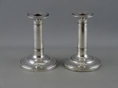 A PAIR OF SILVER CIRCULAR BASED COLUMN CANDLESTICKS with reeded bands, Birmingham 1912 (loaded)