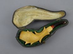 A CASED DECORATIVE SMOKING PIPE with composition bowl and amber stem