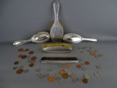 Four various silver backed dressing table brushes and a comb with a quantity of current coinage