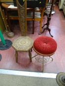 Carved spinning chair with heart shaped cut-out and a circular red upholstered brass framed piano