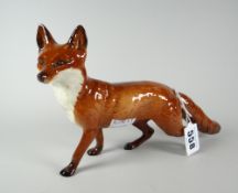 A Beswick standing fox with head peering to his left and brush extended, 24cms long Condition