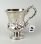 An early Victorian repousse work footed mug with scrolling loop handle and with silver gilt