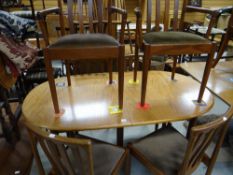A mid-century oval extending dining table having a pop-up centre leaf and six matching chairs (G-