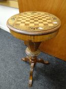 An antique circular topped marquetry games table / sewing box on carved tripod supports, 46cms diam.