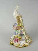 A Royal Crown Derby porcelain peacock model perched on an urn of flowers, decorated in gilding and