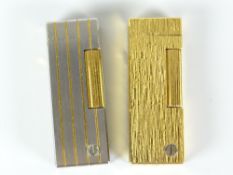Two Dunhill gas cigarette lighters - a bark textured gold plated example and a white metal version