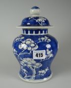 A Chinese pottery baluster vase and cover decorated in blue and white Prunus, 19cms high Condition