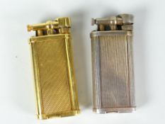 Two Dunhill gas cigarette lighters, gold metal engine turned and white metal ribbed body example