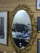 Gilt and scroll framed oval wall mirror, 63 cms long