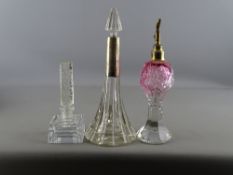 Three vintage cut and other glass scent bottles, one with long silver collar, another cranberry