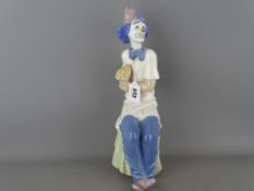 34 cms high Nao porcelain figurine of a seated clown holding a bunch of flowers