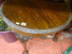 Reproduction mahogany circular side table having carved top detail and knees on ball and claw feet