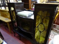 Ornately carved display cabinet having a central glazed bow front door with flanking doors over a