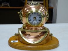 Modern Quartz clock in the form of a diver's helmet in copper and brass on an oval wooden plinth