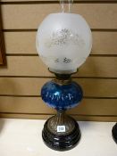 Metal stemmed oil lamp with blue glass reservoir and etched shade