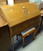 A mid-century imported hardwood sloped bureau with carved motif to the front and with stool, 91cms