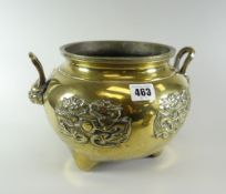 A Chinese polished bronze twin-handled tri-foot censer with relief dragon decoration and lion