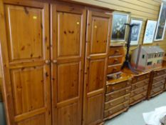 A suite of modern honey-pine bedroom furniture including triple wardrobe and four chests of