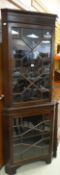 An antique mahogany standing corner cabinet with astragal glazed base and top and having a dentil