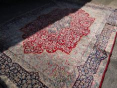 A large Persian Kashan rug with red centre decoration and blue and gold border, 410 x 292cms (A/F)