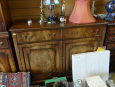 A Bevan Funnell reproduction mahogany sideboard having two cupboard doors and two drawers with brass