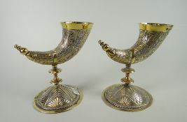 A pair of silver gilt vases in the form of carved hunting horns raised over circular bases by