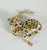 A 9ct yellow gold gem set leopard brooch, the body set with tiny sapphires and the eyes ruby set,