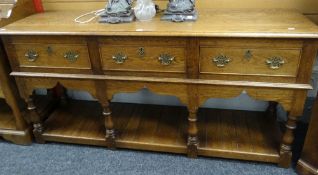 A good reproduction oak dresser-base composed of floor level planked platform and with three drawers