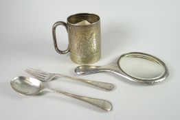 An engraved silver mug, silver spoon and matching fork set and a monogrammed silver backed mirror