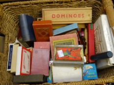 A modern basket containing mid-century and vintage playing card games, sets of domino's ETC