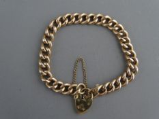 A NINE CARAT GOLD CURB BRACELET with padlock clasp and safety chain, 13.2 grms