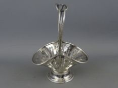 A MINIATURE SILVER SHAPED BASKET on a circular base and with a double intertwined centre handle,